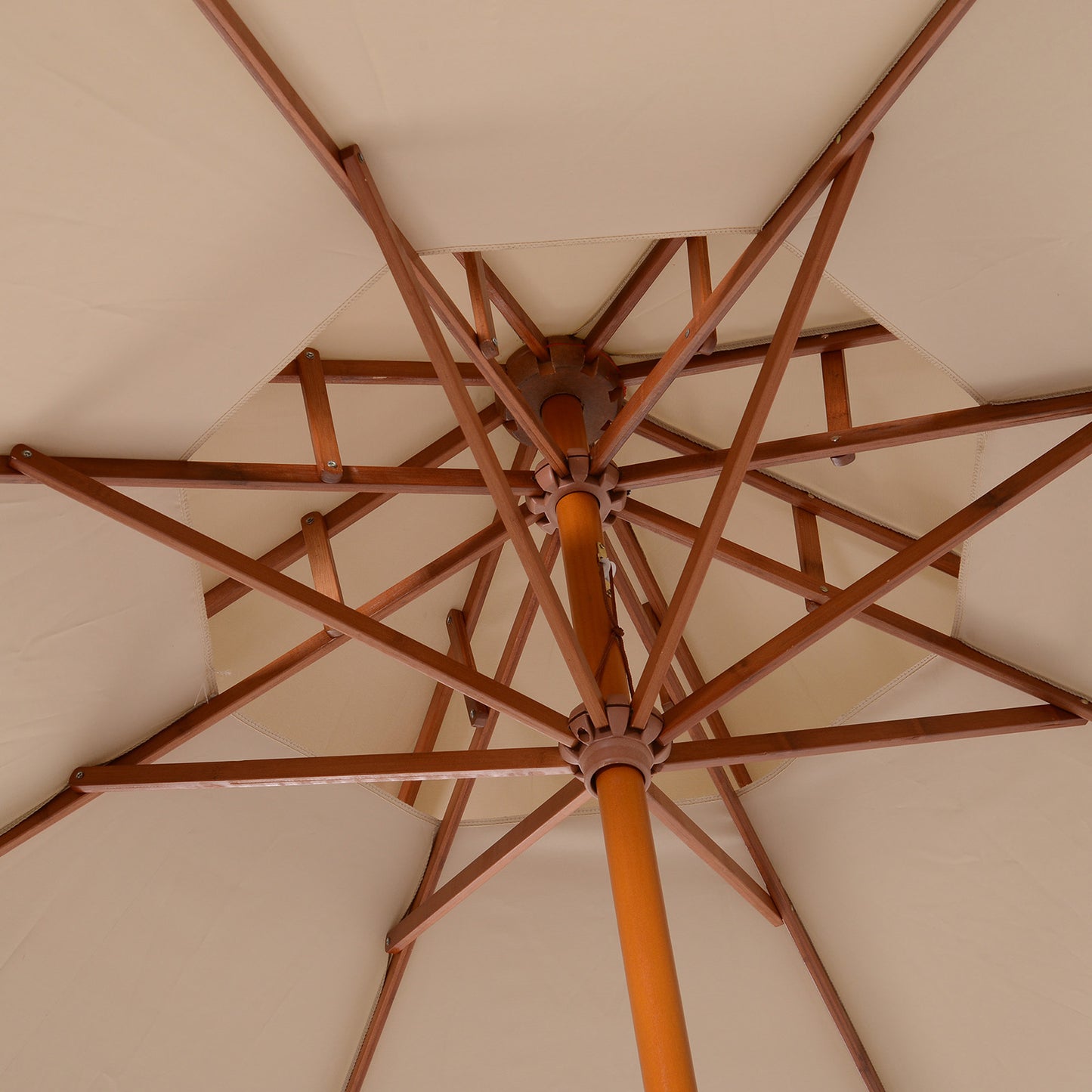 Underside of the beige parasol showing wooden ribs and central pole