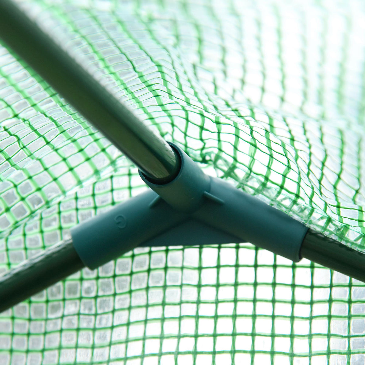 Close-up of a plastic connector joining steel greenhouse frame poles beneath the mesh cover