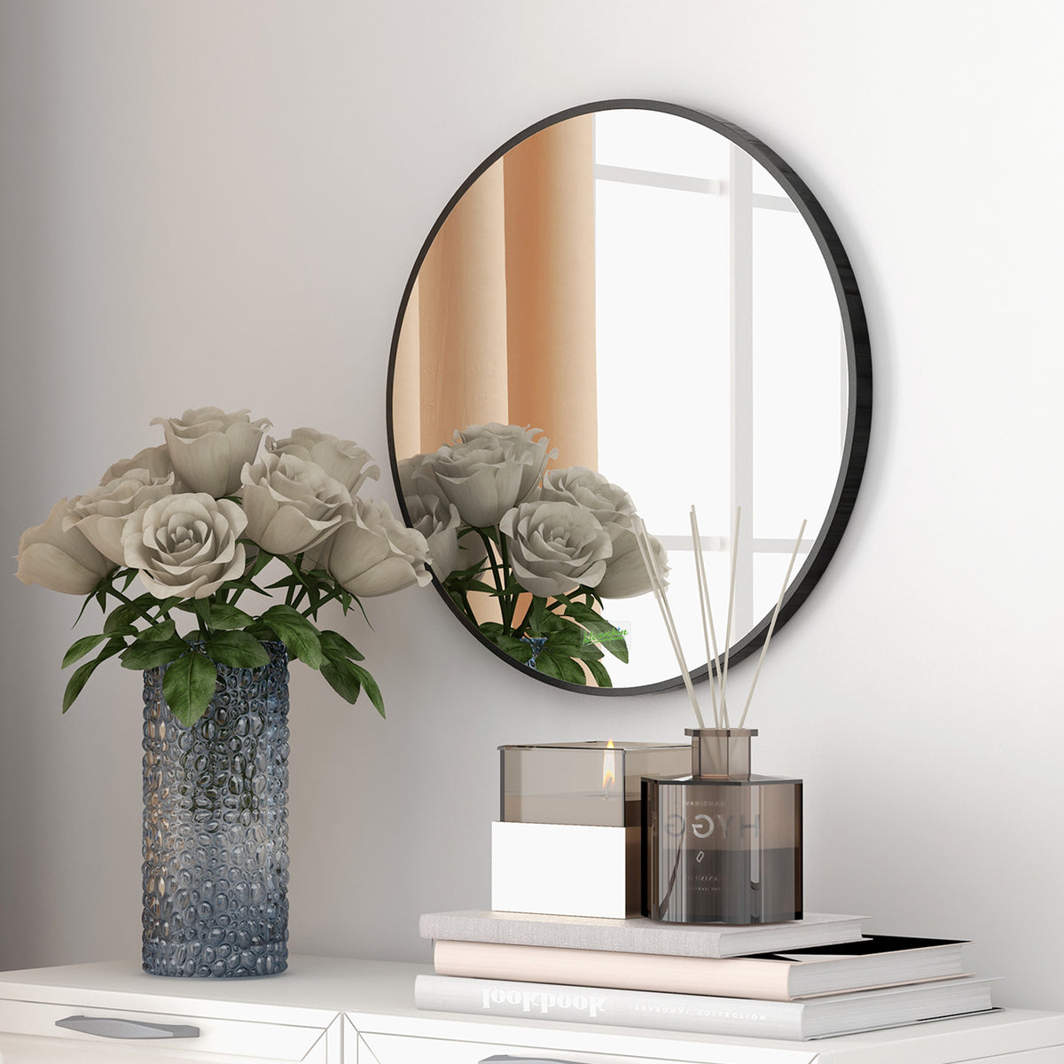 Round black-framed wall mirror above a console, with flowers reflected in the glass.