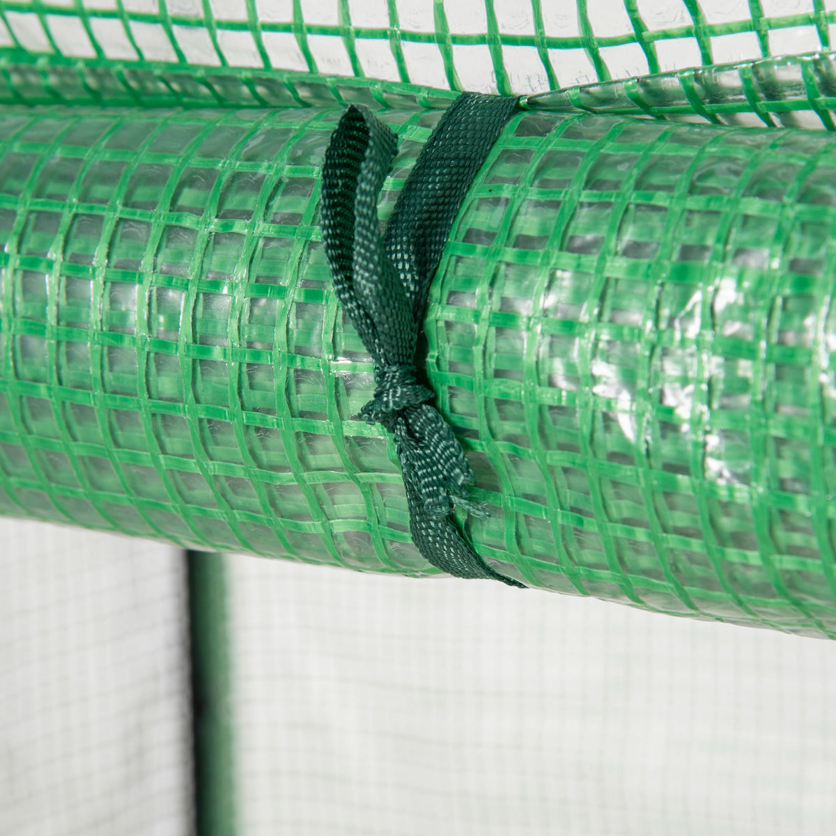 Green greenhouse cover rolled up and secured with a strap