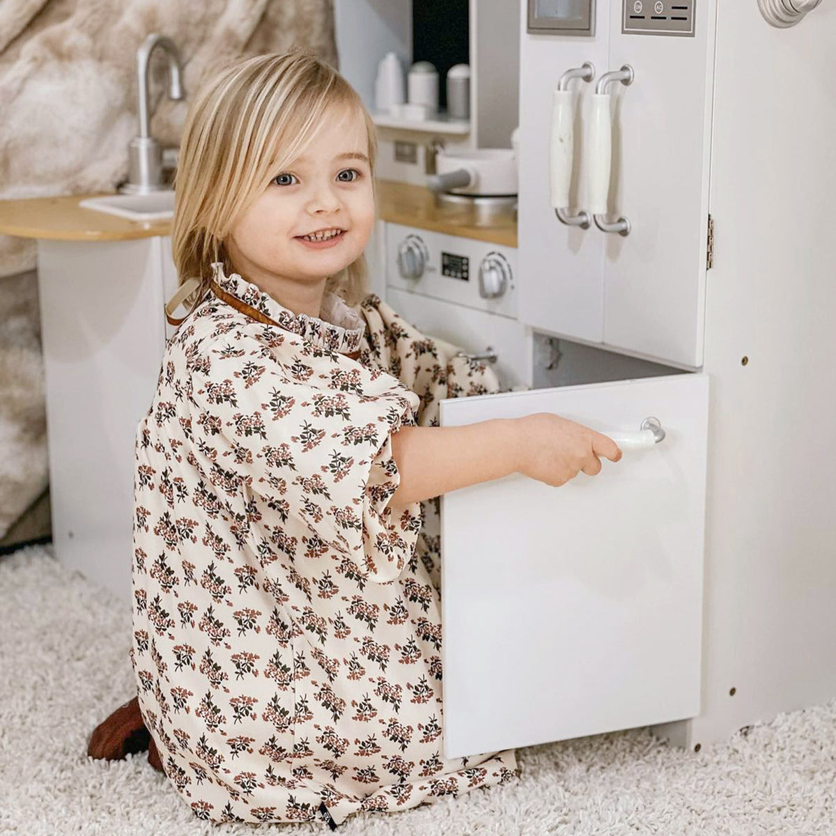 HOMCOM white play kitchen with a child opening a lower cabinet door