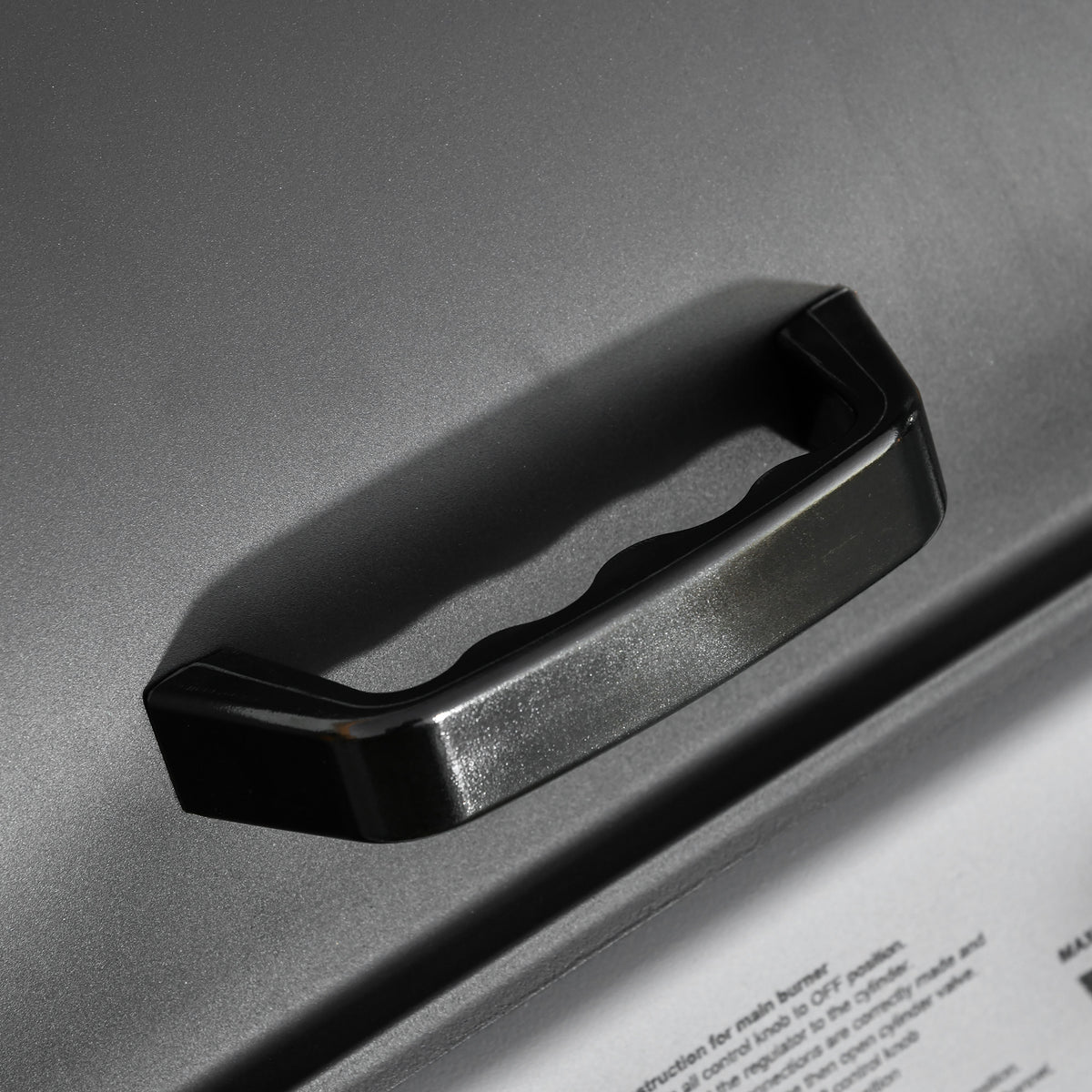 Close-up of the black handle on the BBQ grill lid