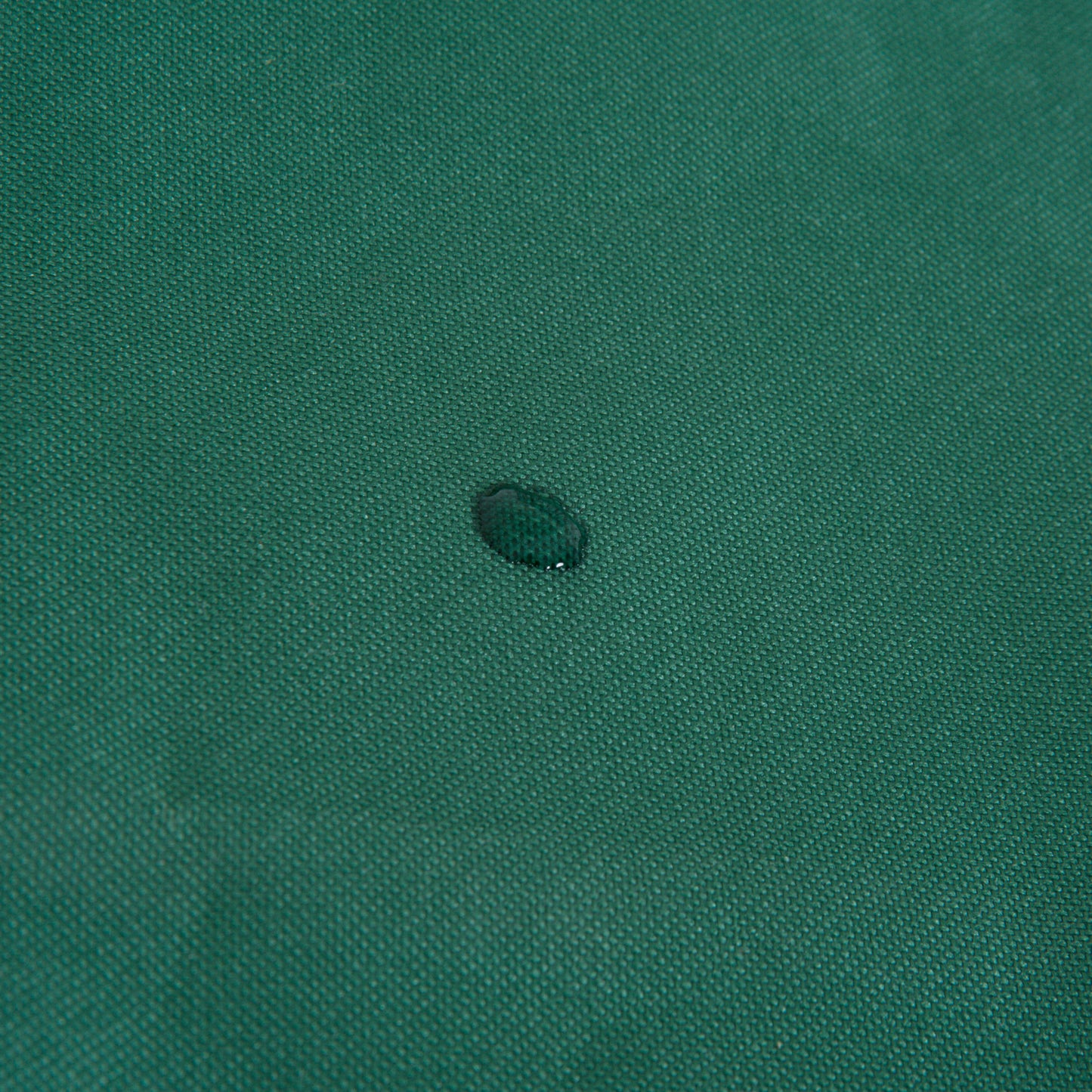 Green furniture cover fabric with a water droplet on its textured surface