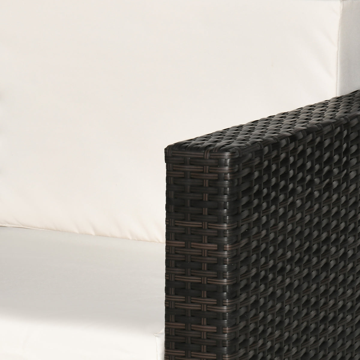 Close-up of the woven rattan armrest beside the white cushions