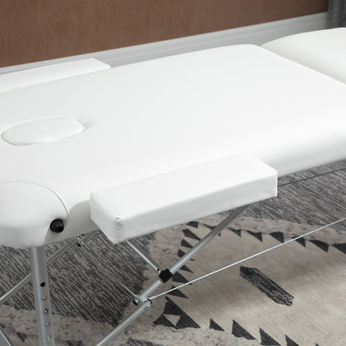White massage table with a removable padded armrest and face opening