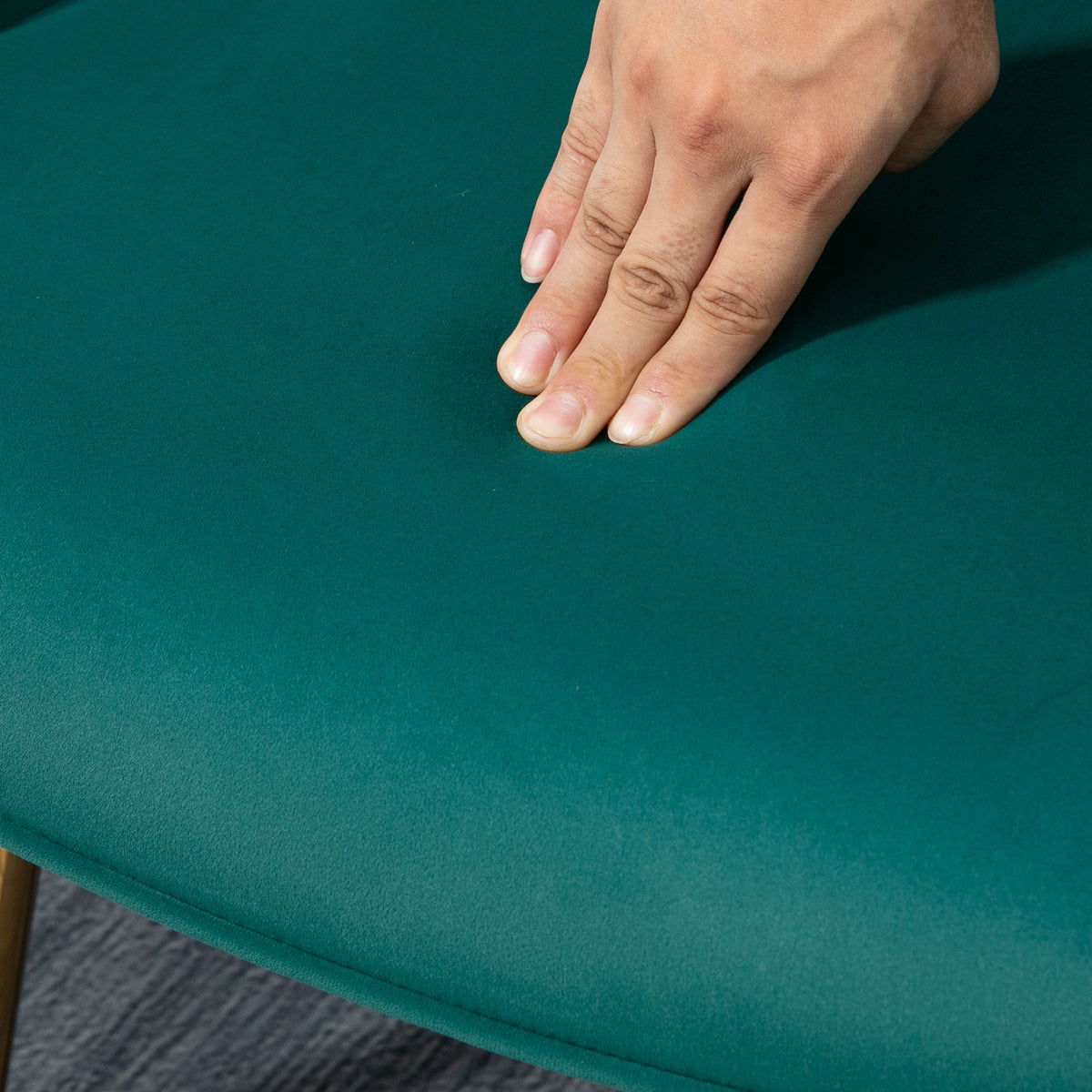 Dark green upholstered armchair seat with soft velvet-feel fabric under a hand