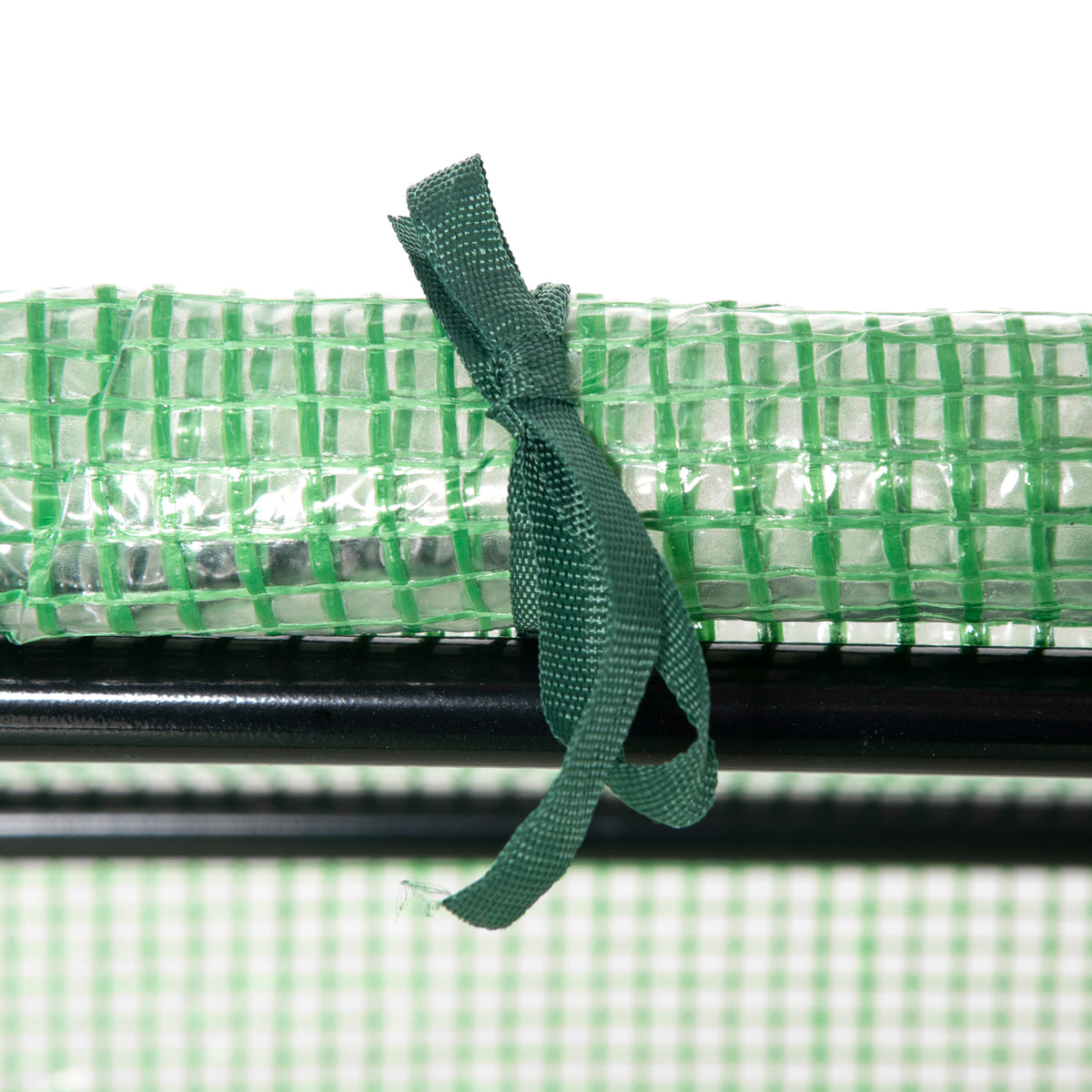 Green greenhouse cover secured to its frame with a tie strap