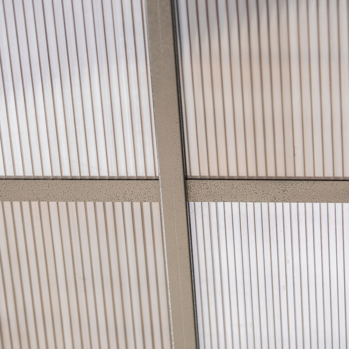 Close-up of translucent polycarbonate roof panels and grey support bars