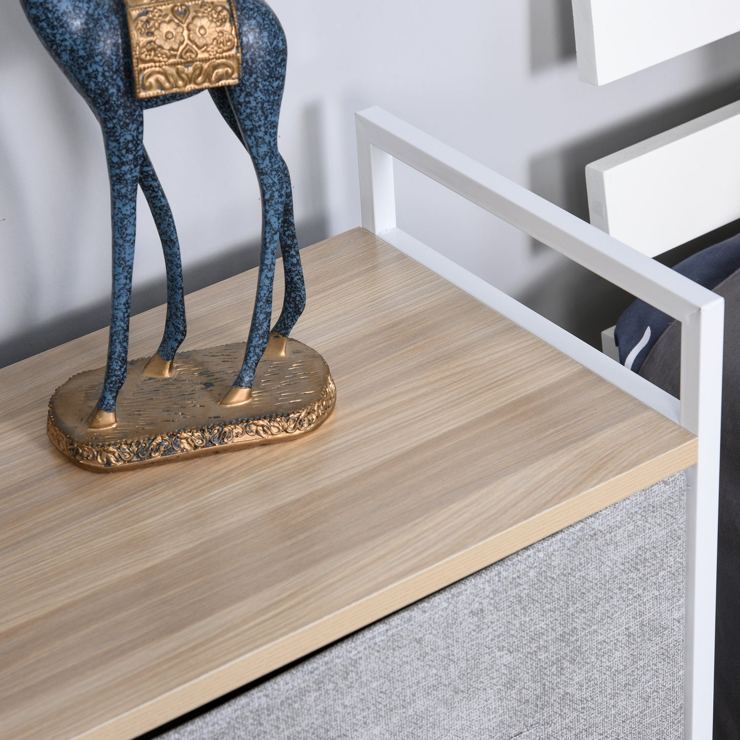 Close-up of the storage unit's wood-look tabletop and white metal side rail
