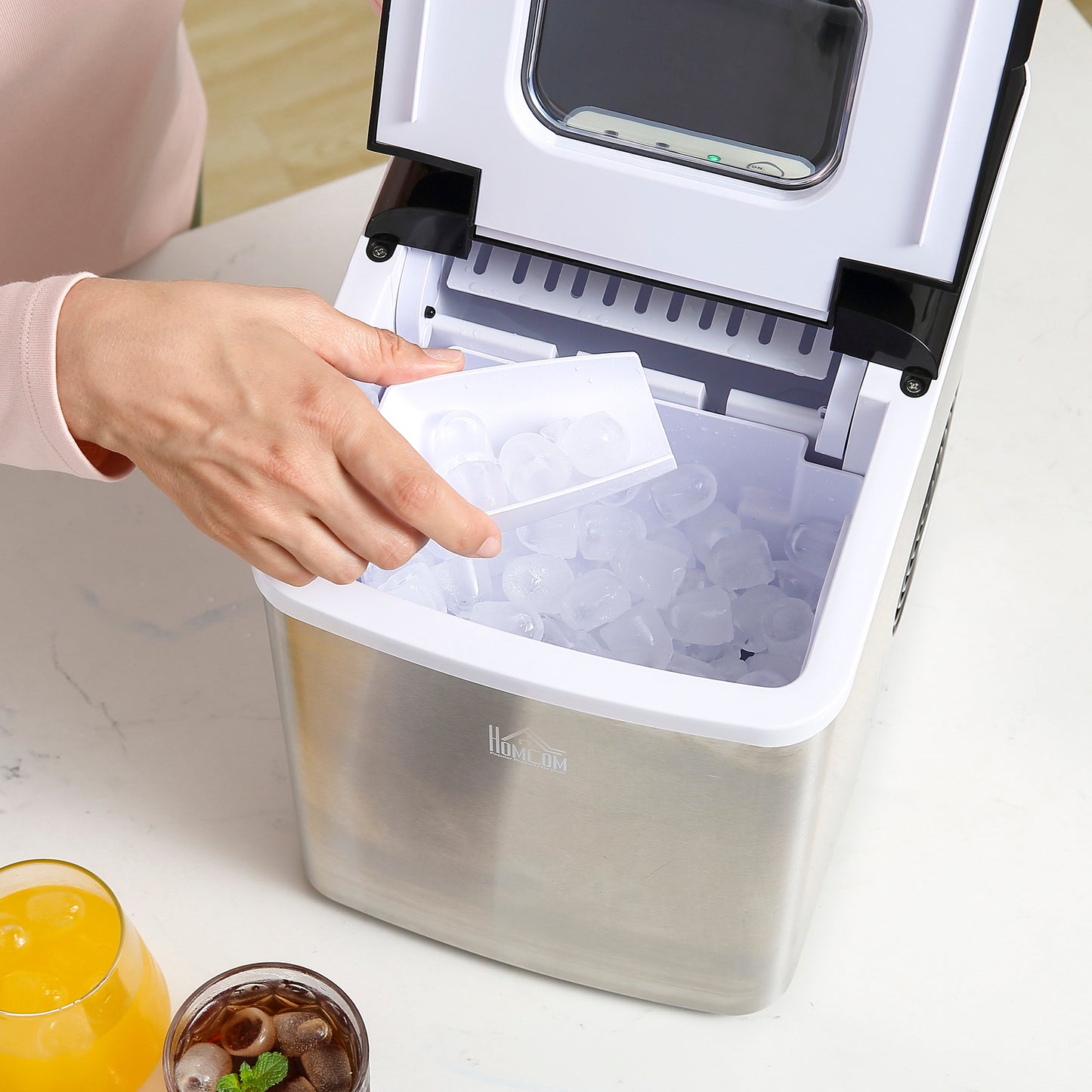HOMCOM ice maker open as a hand scoops ice from the filled bin