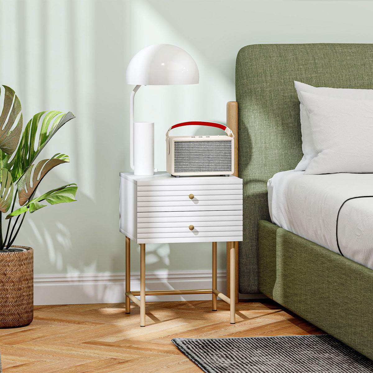 White two-drawer bedside table with gold-tone legs beside a bed