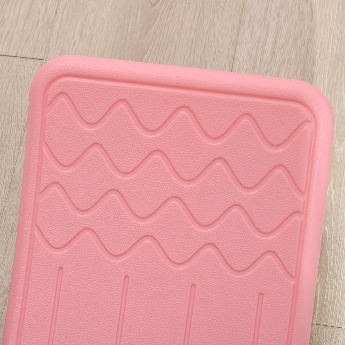 Close-up of the pink balance board's raised wavy texture and molded foot grip.