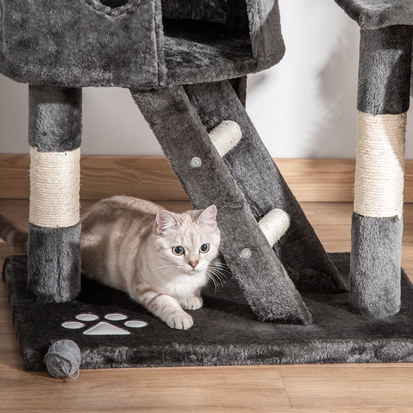 Dark gray cat tree base with sisal posts and ladder beside a cat