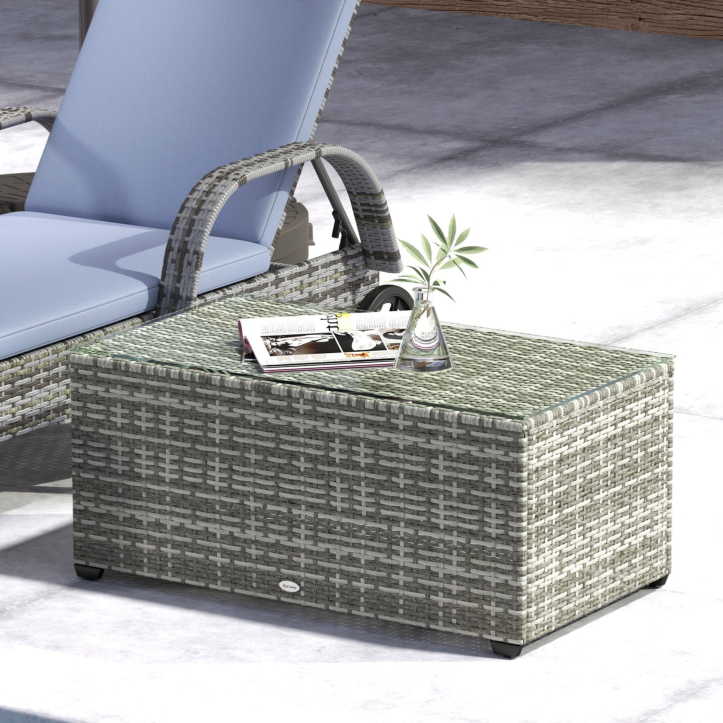 Light grey woven rattan side table with glass top beside a lounge chair