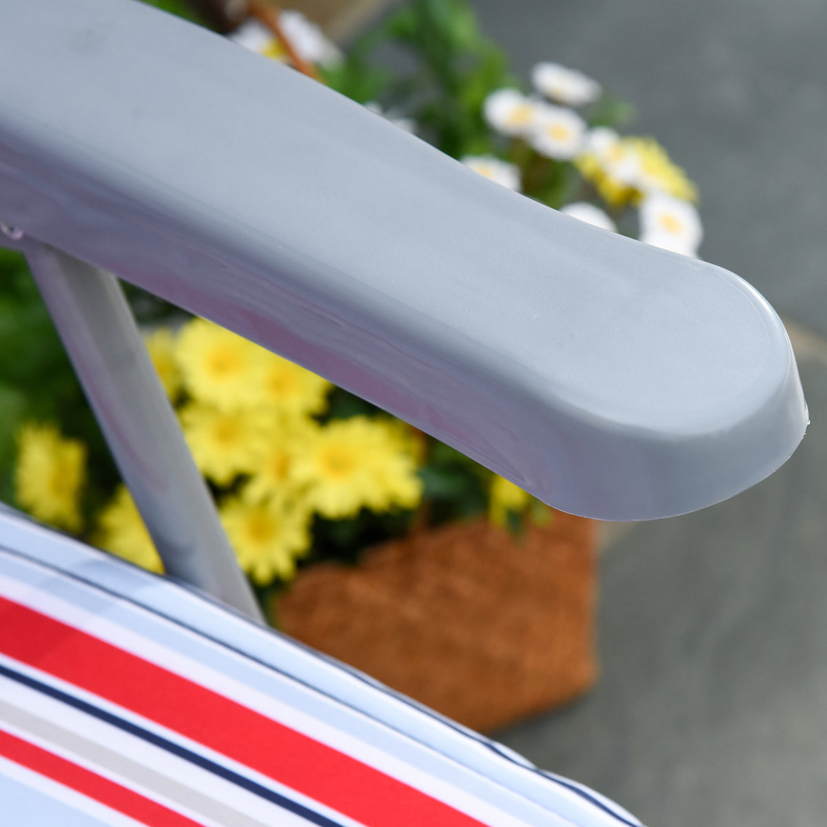 Close-up of a gray chair armrest above the red, white, and blue striped cushion