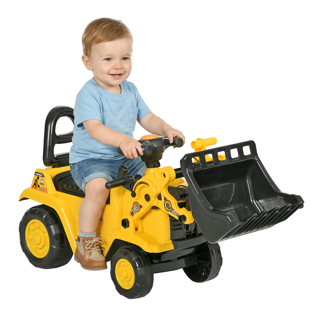 Toddler riding a yellow ride-on excavator with a large black front bucket.