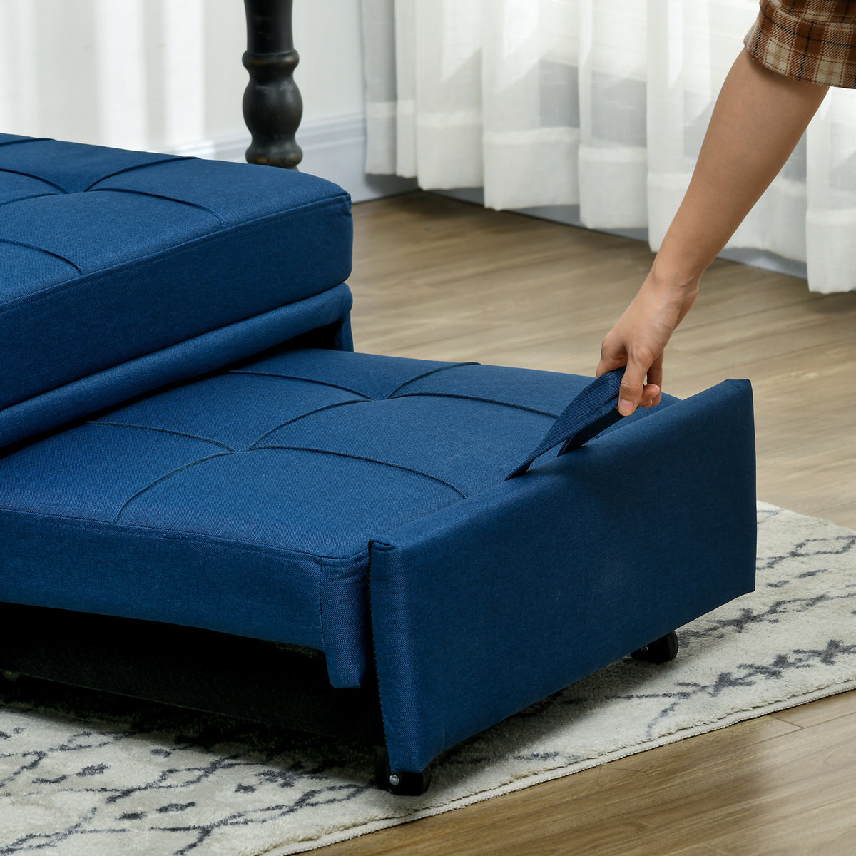Blue sleeper chair with pull-out footrest being extended by its fabric handle.