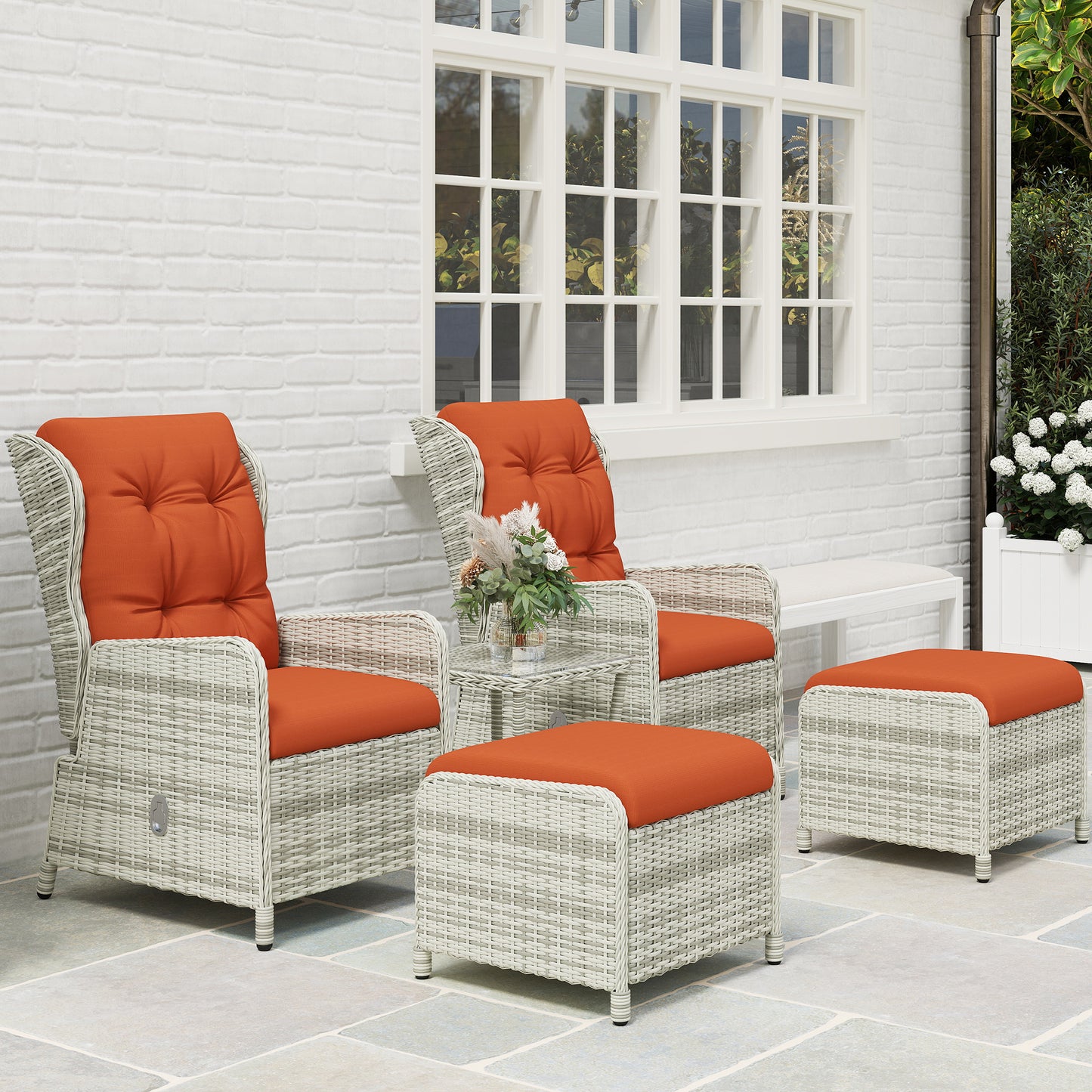 Five-piece wicker patio set with two orange-cushioned chairs, table and footstools