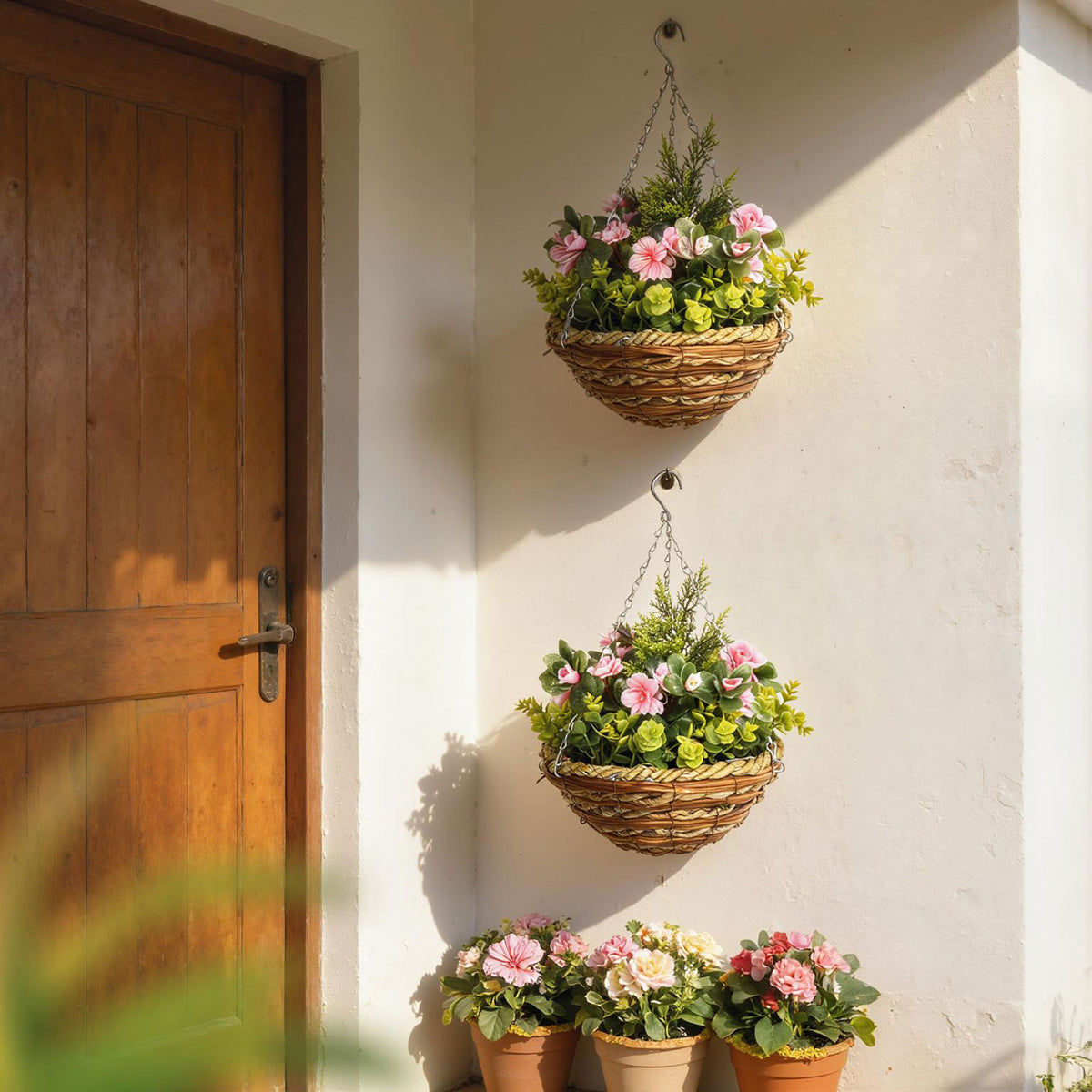 Two woven hanging baskets with pink flowers and green foliage, displayed above matching potted flowers