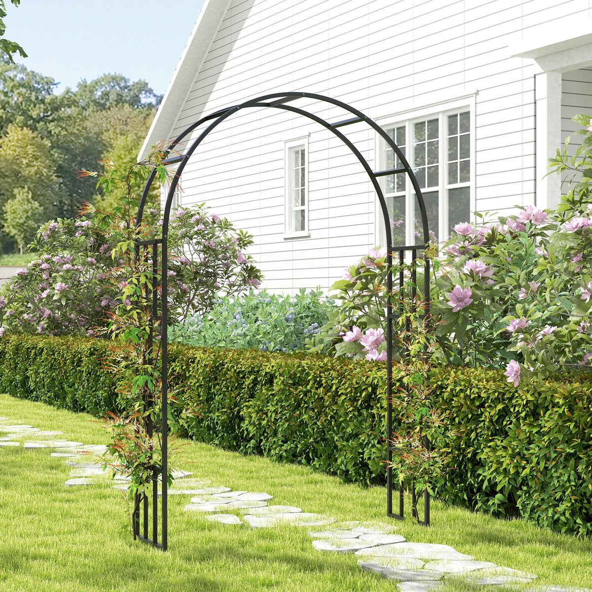 Black metal garden arch framing a path, with flowering climbing plants on its sides