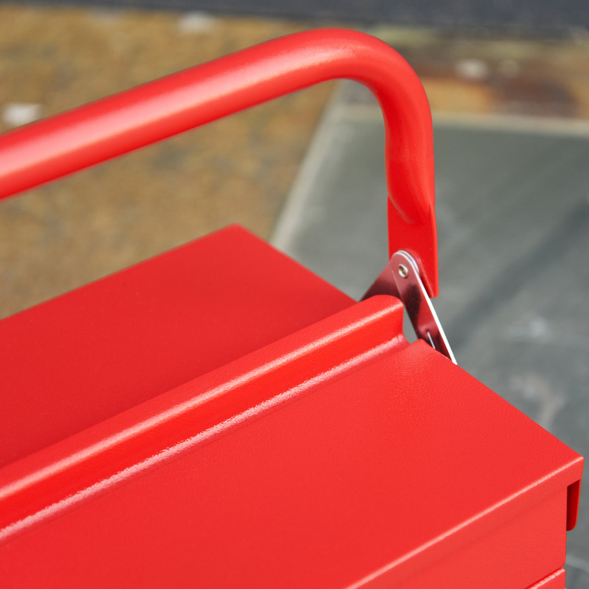 Close-up of the red toolbox handle and metal hinge attachment