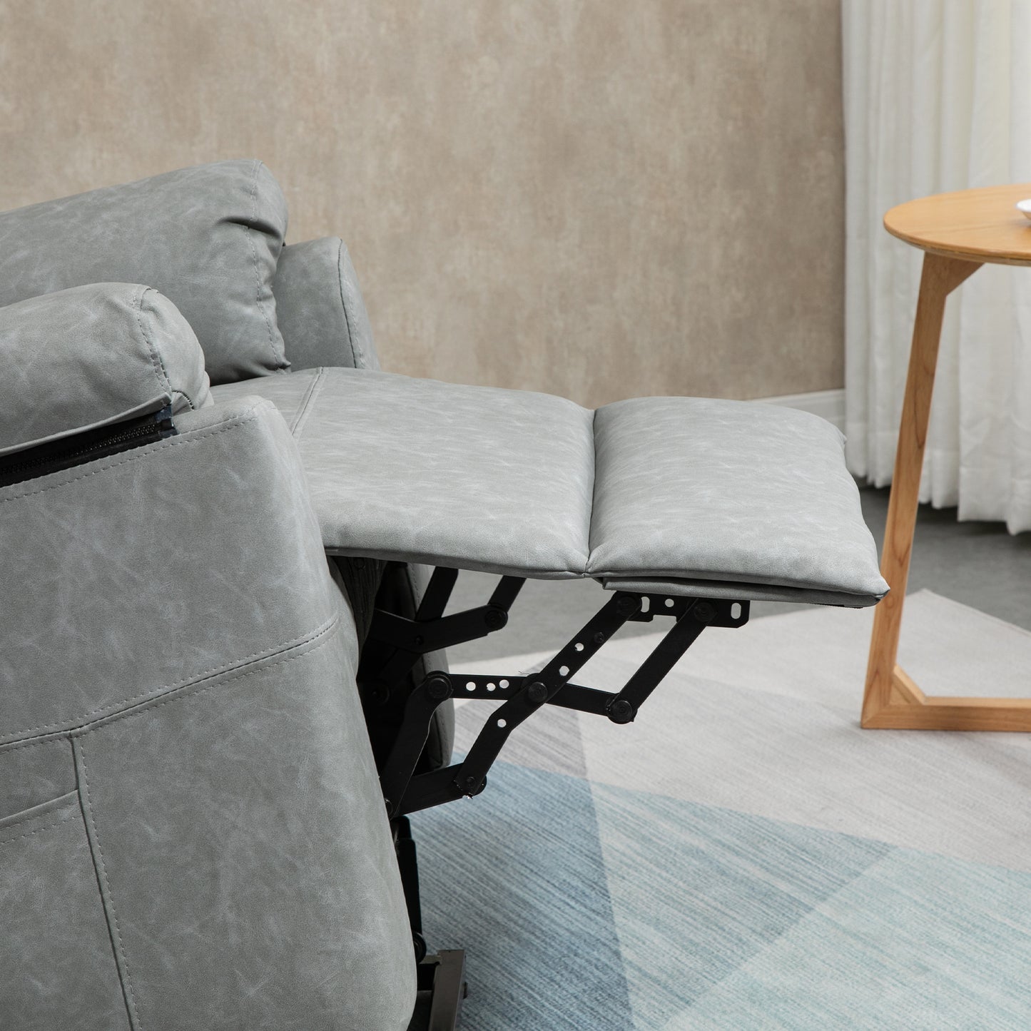 Grey faux leather recliner with extended padded footrest and visible lift mechanism
