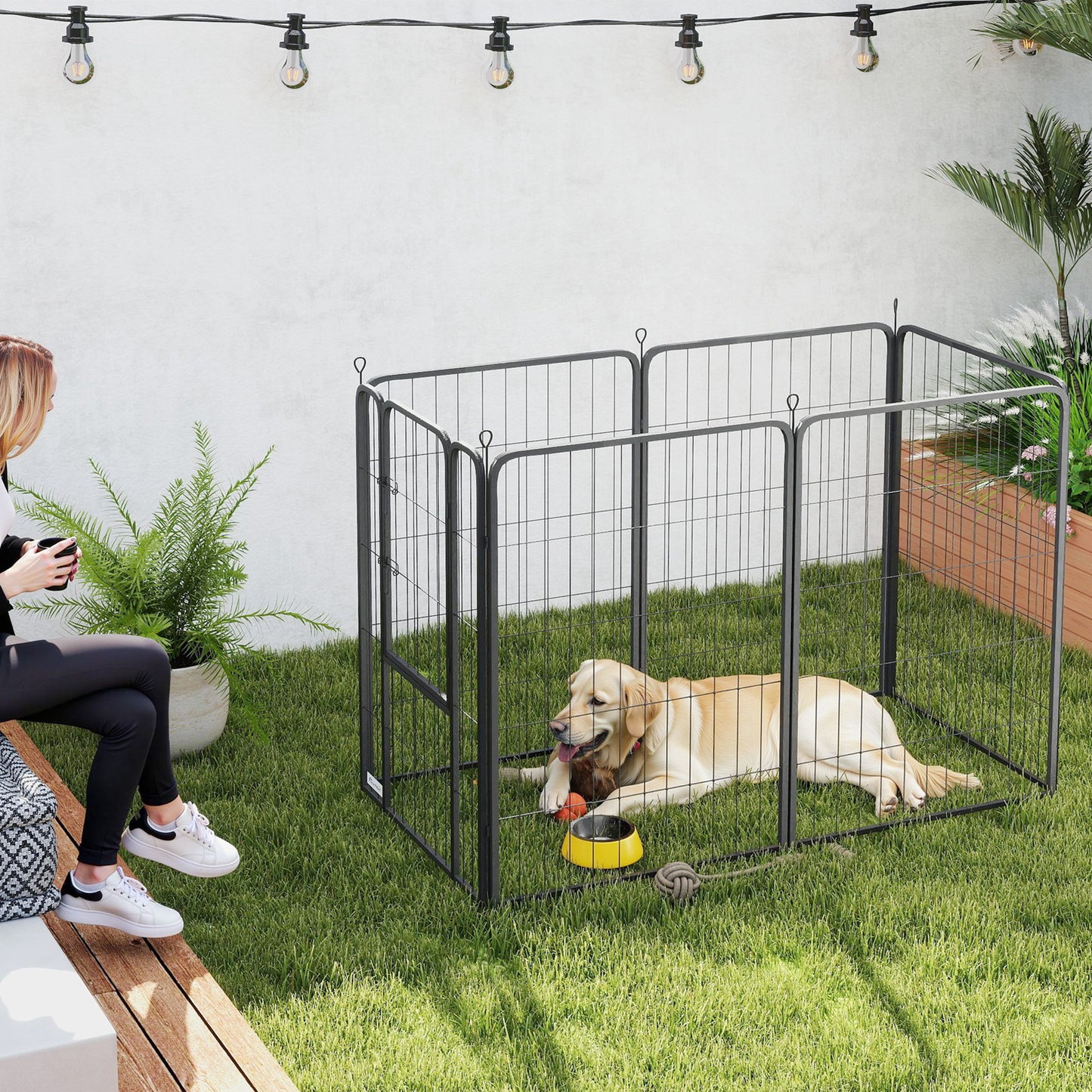 Black six-panel dog playpen set up outdoors with a dog inside