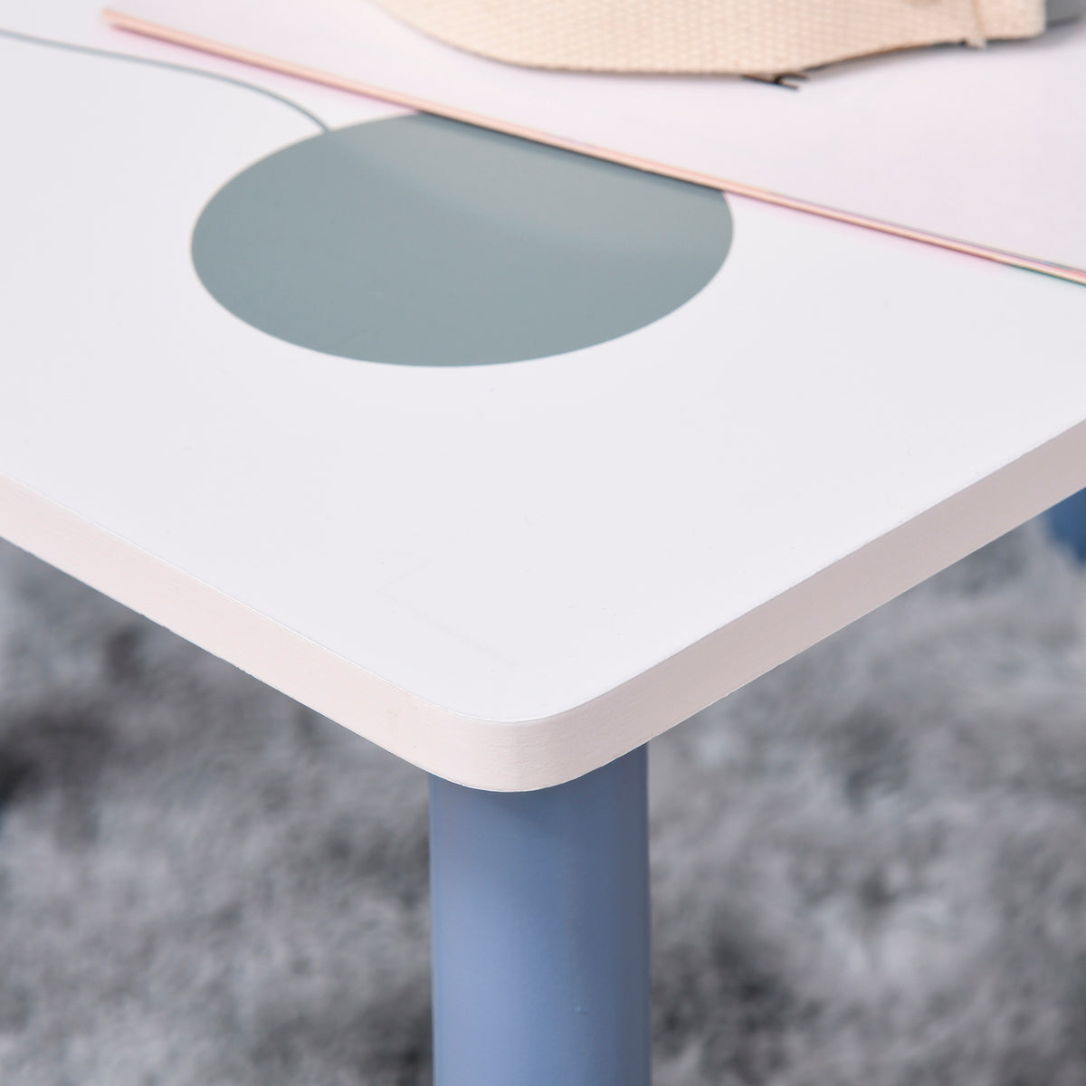 Close-up of a kids' table with a rounded white top and blue leg.