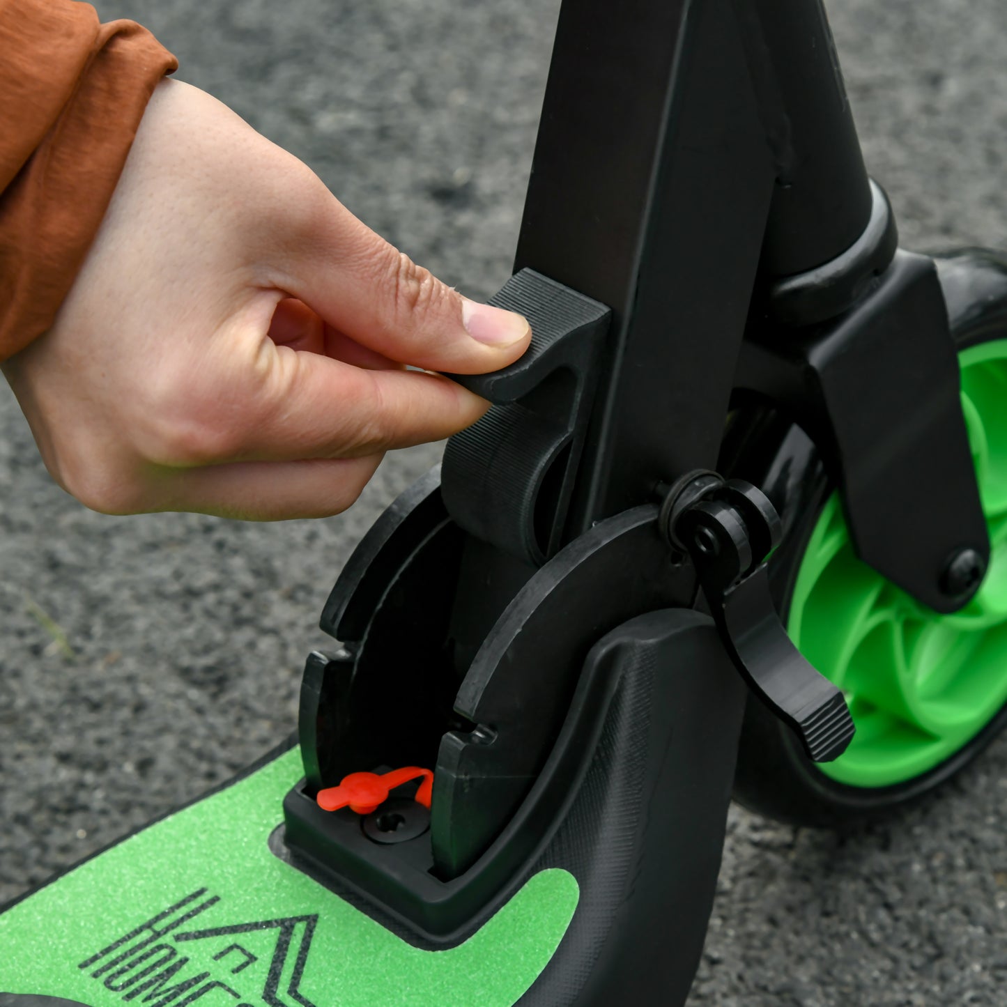 Close-up of the folding latch and green deck on a black HOMCOM electric scooter