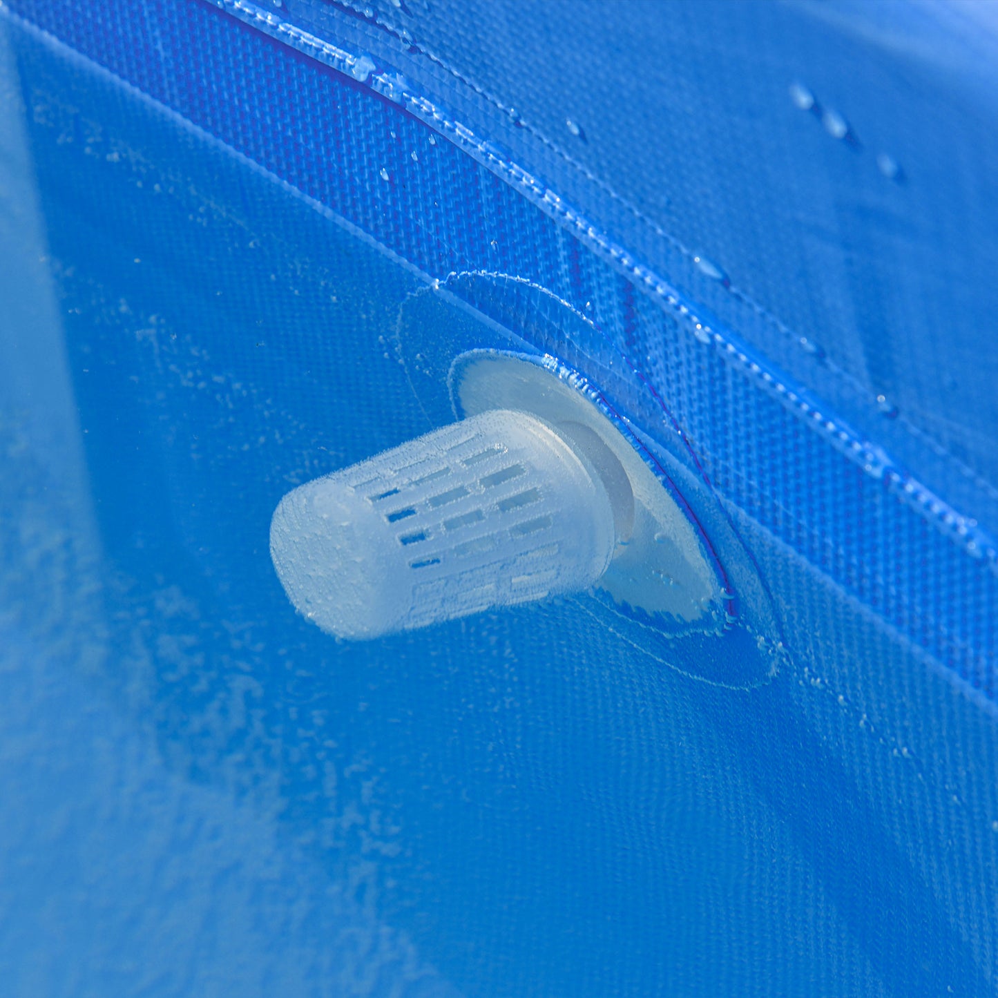 Close-up of a white slotted pool filter fitting on the blue sidewall