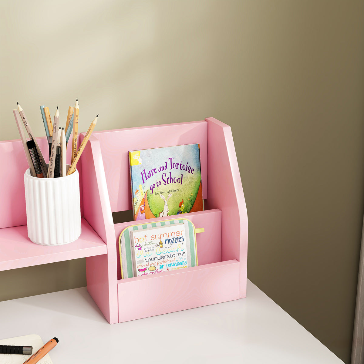 Pink desk hutch compartment holding books beside a pencil cup