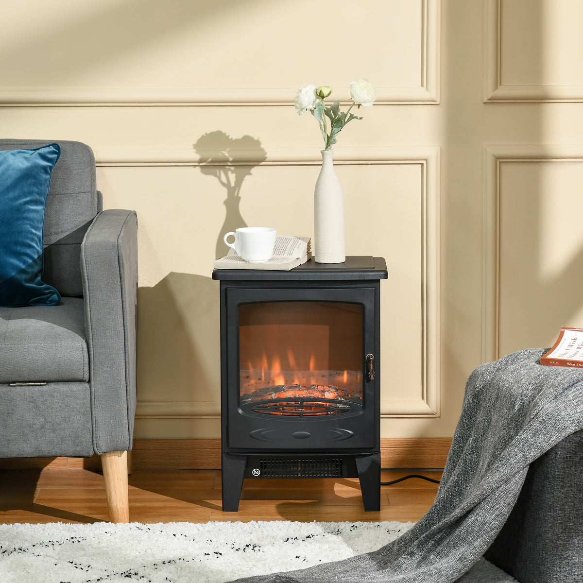 Black electric fireplace stove with glowing flames beside a sofa