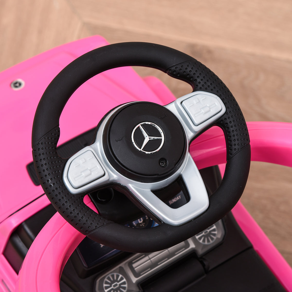 Close-up of black and silver steering wheel on a pink ride-on car