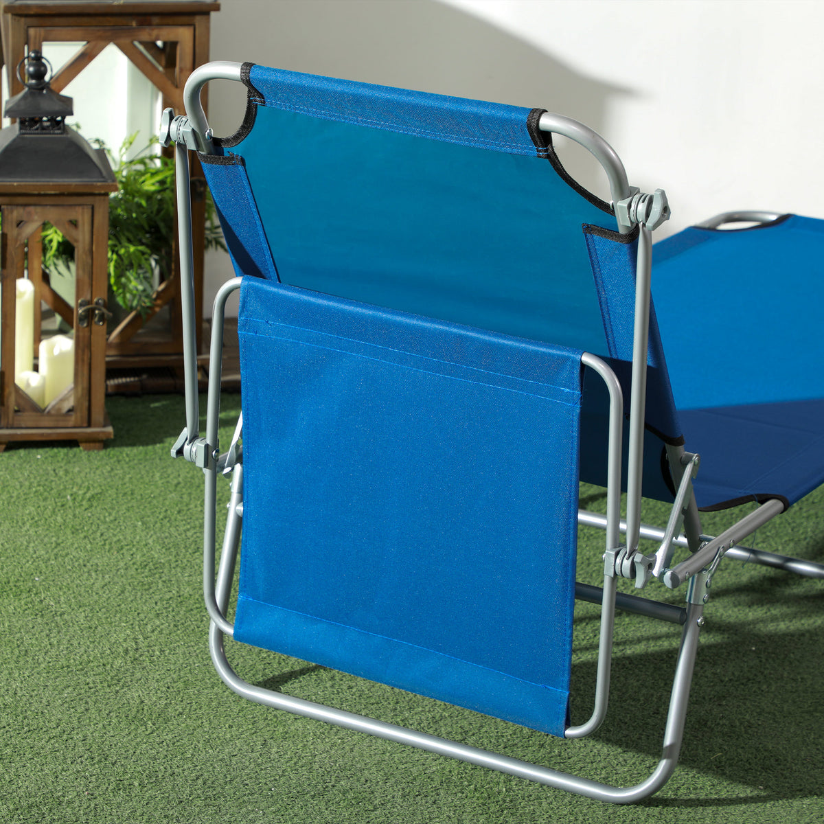 Blue folding sun lounger shown folded, with its silver frame and fabric seat