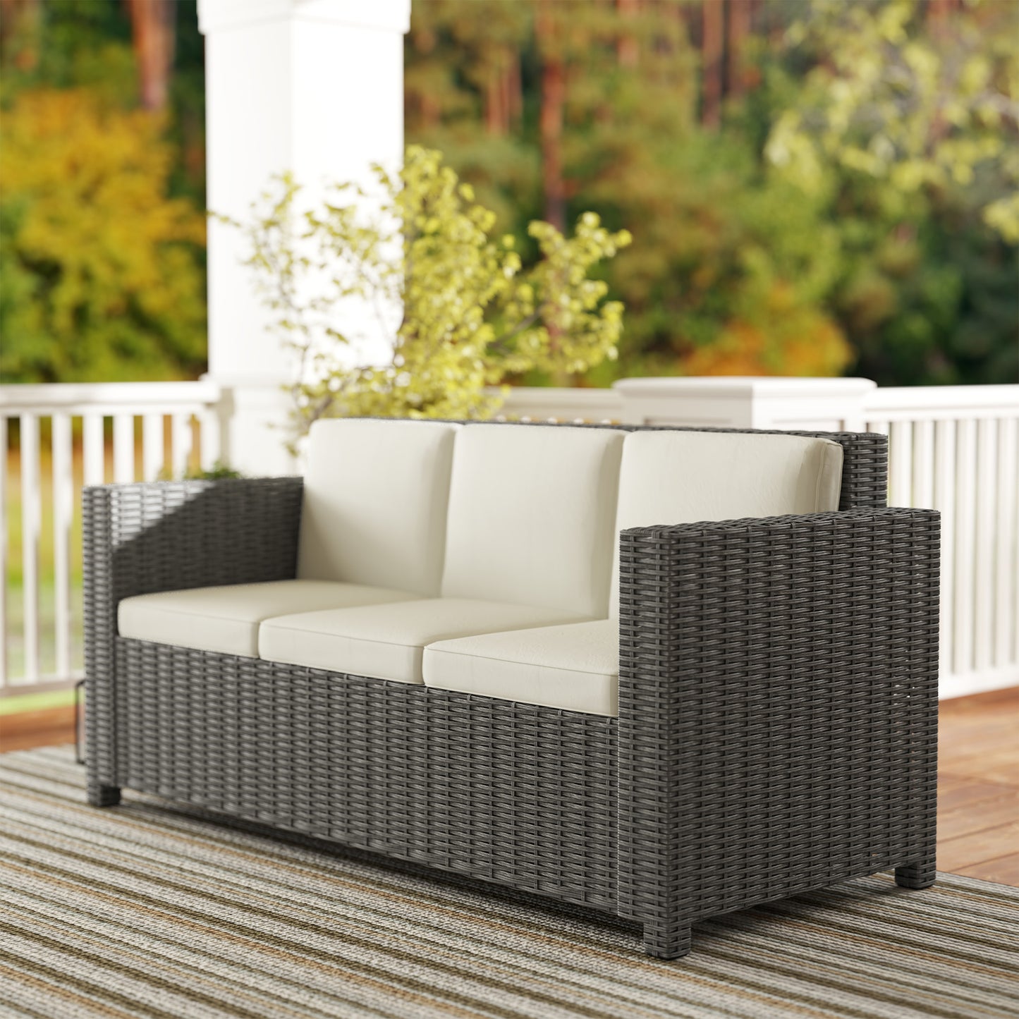 Three-seat rattan sofa with deep woven arms and cream cushions