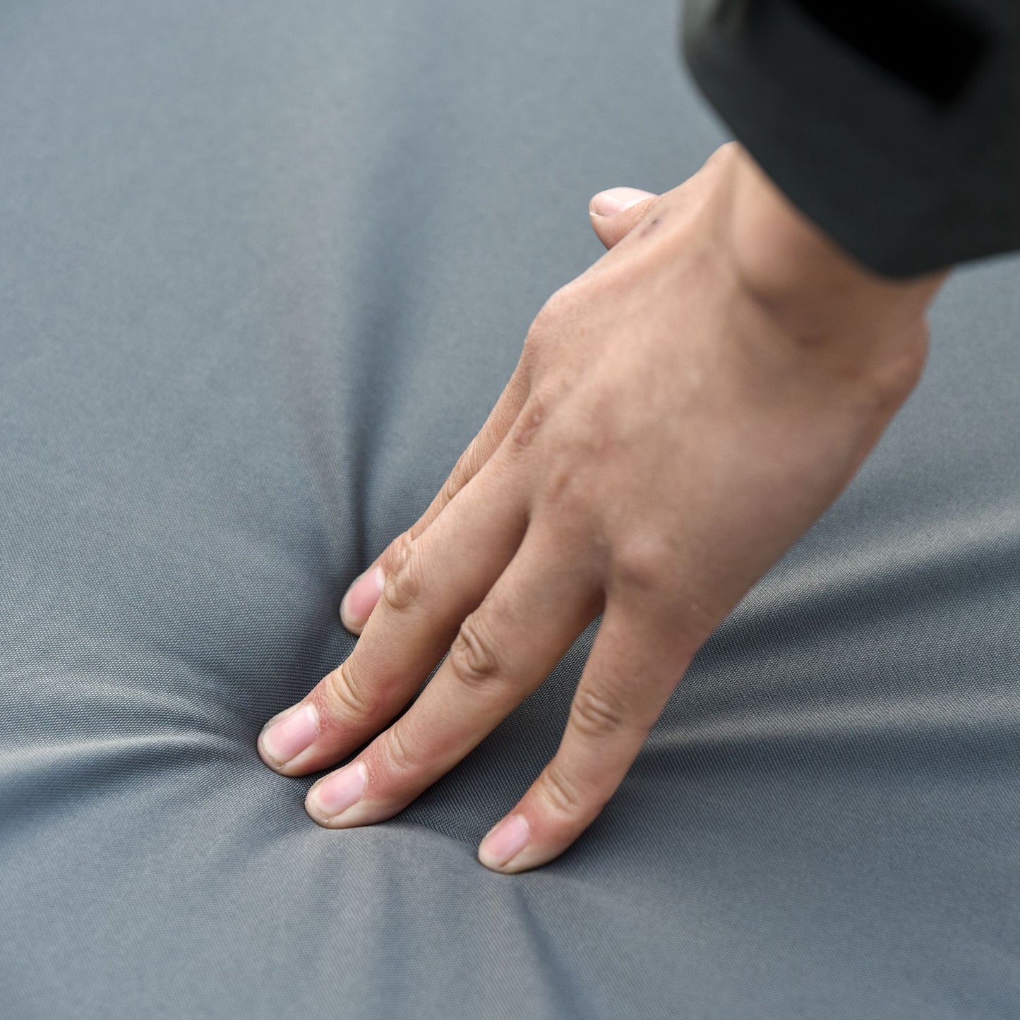 Close-up of a hand pressing into a soft gray sofa cushion