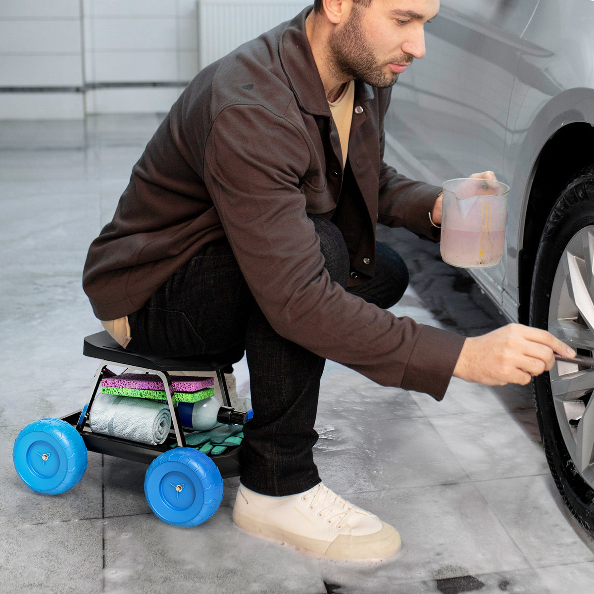 Garden storage cart used as a seat while cleaning a car, with supplies on its tray