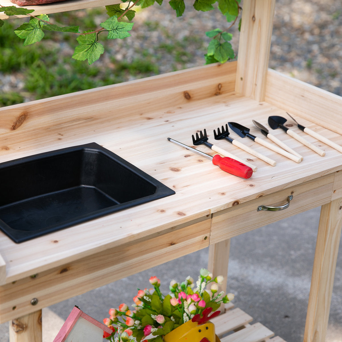 Wooden potting bench worktop with black sink, hand tools, and front drawer