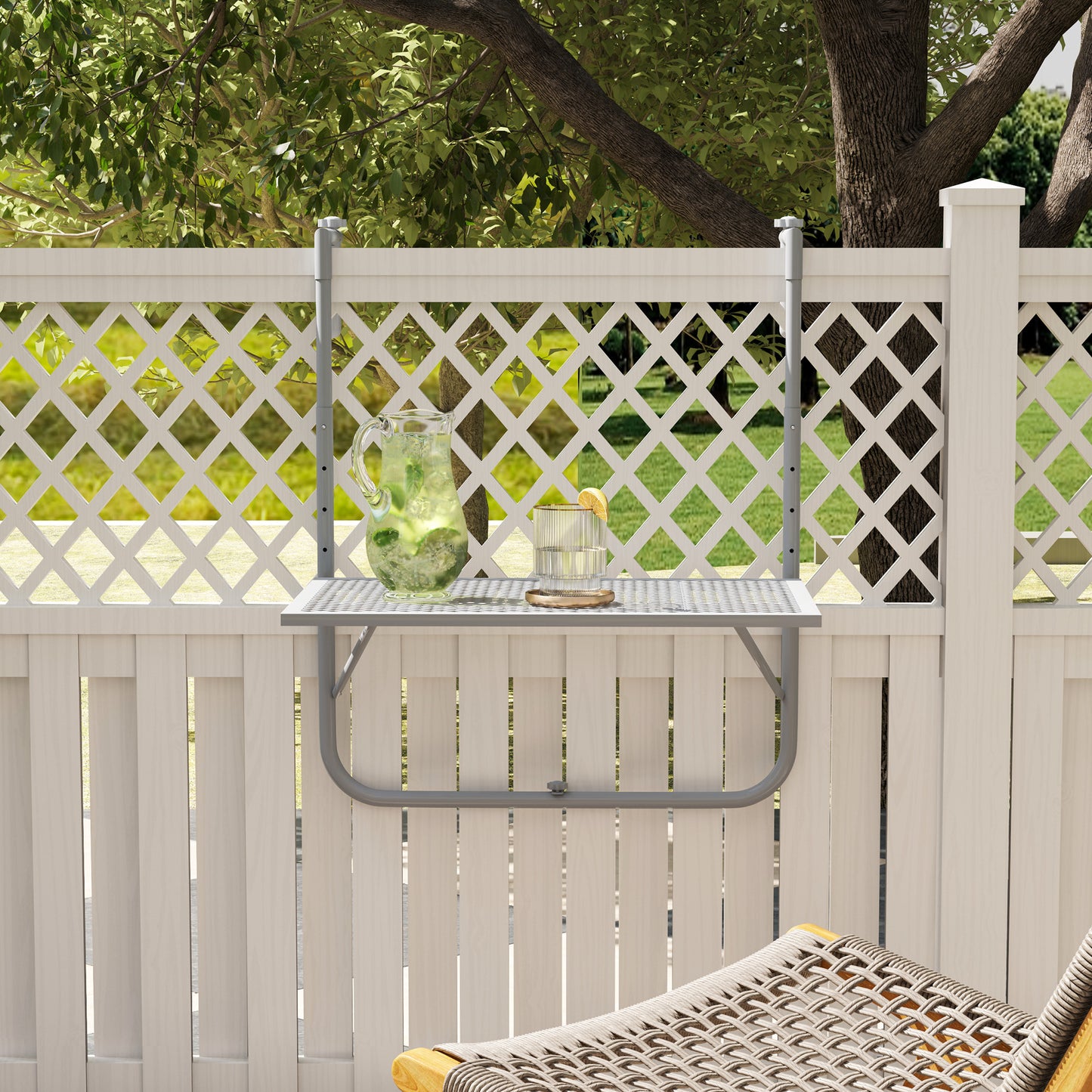 Grey hanging table mounted on a fence, with a pitcher and glass on its grid top