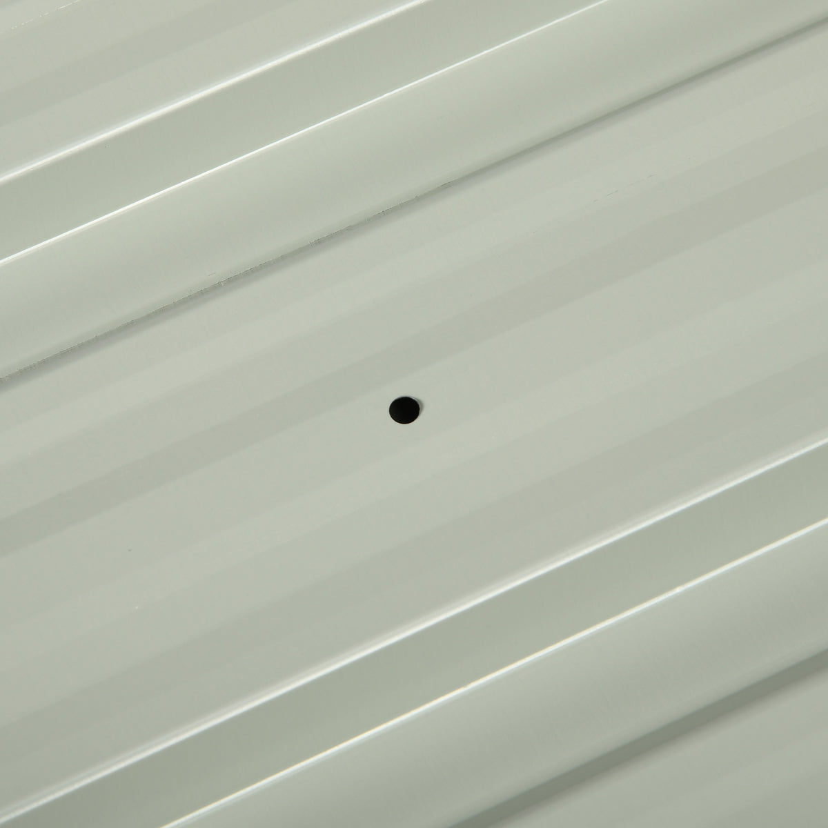 Close-up of a corrugated steel roof panel with a pre-drilled hole