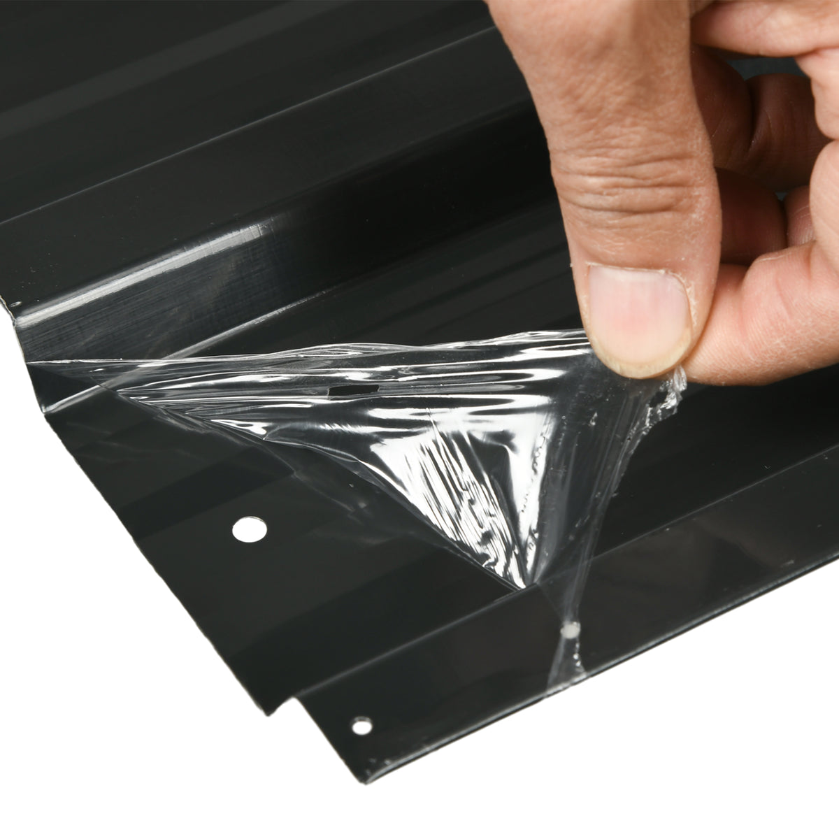 Dark gray corrugated steel roof panel with protective film being peeled back