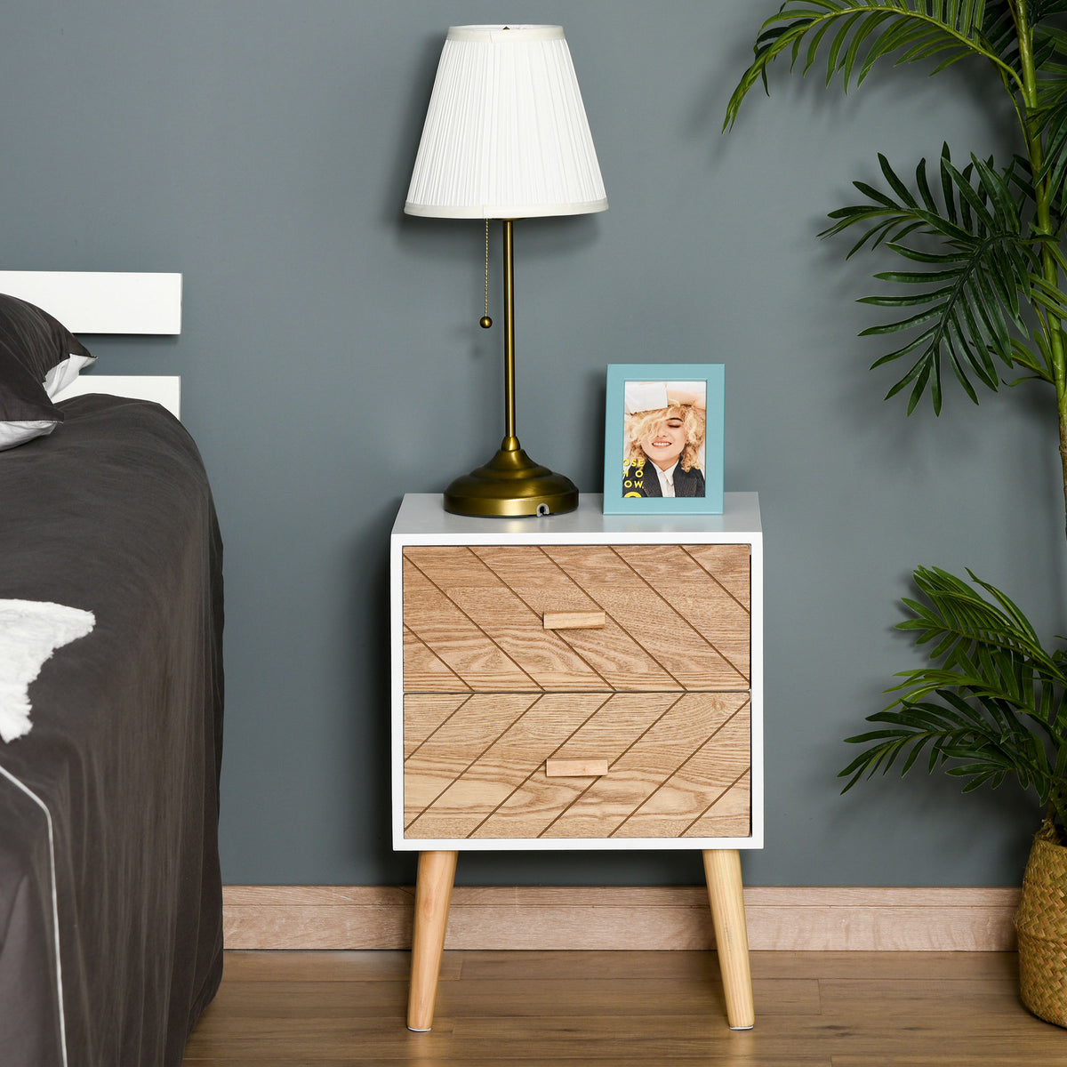 Two-drawer bedside table with geometric wood-patterned fronts beside a bed