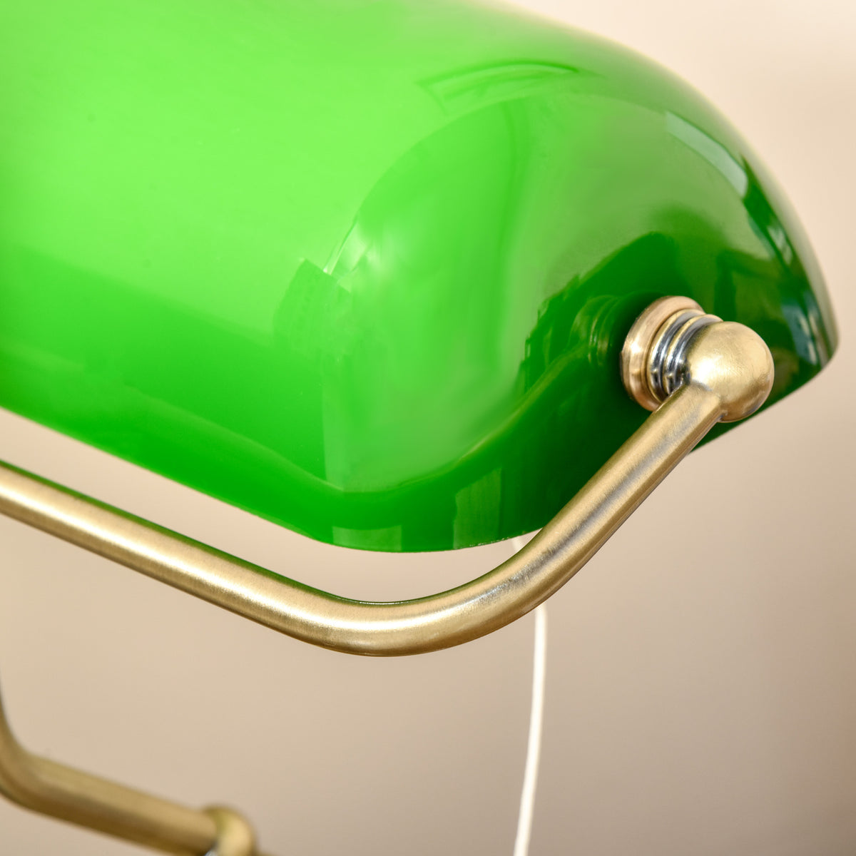 Banker's desk lamp close-up of green glass shade and bronze-tone arm