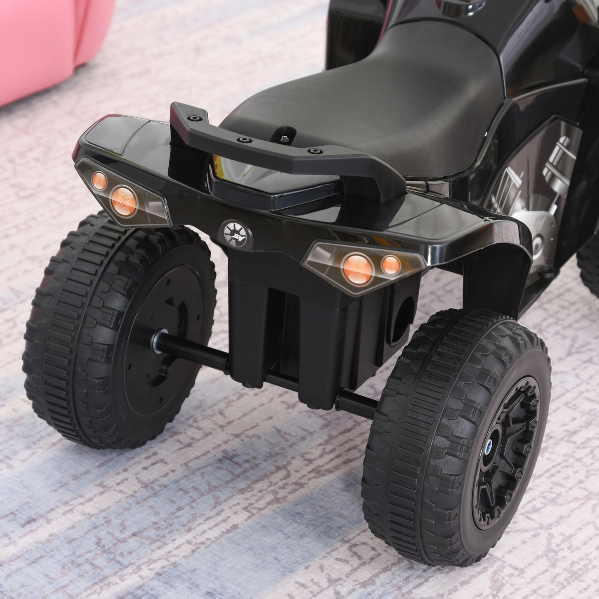 Rear view of the black ride-on quad showing its tail lights, seat, and wide tires.