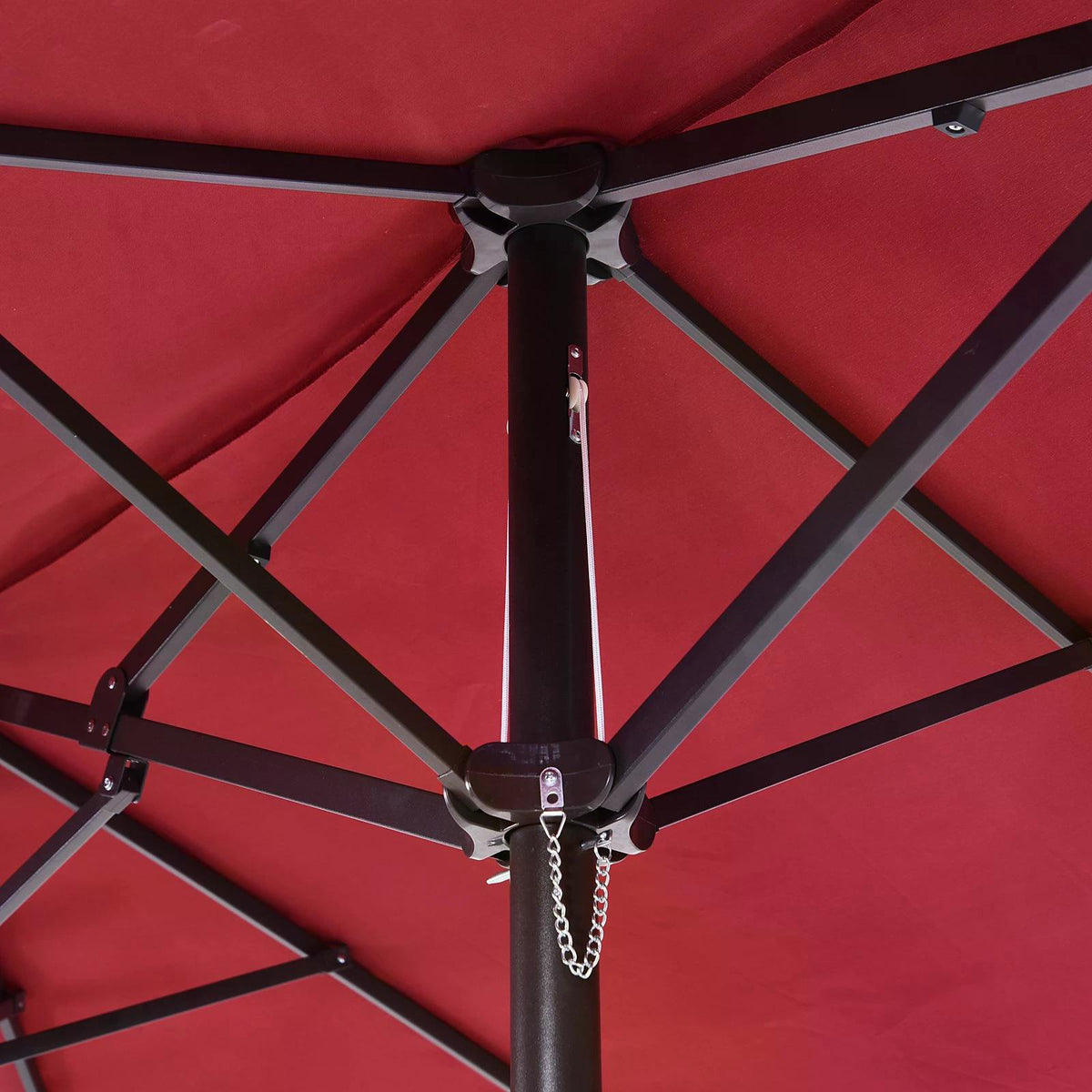 Close-up of the wine-red parasol's underside, showing the dark metal ribs, hub, and pole