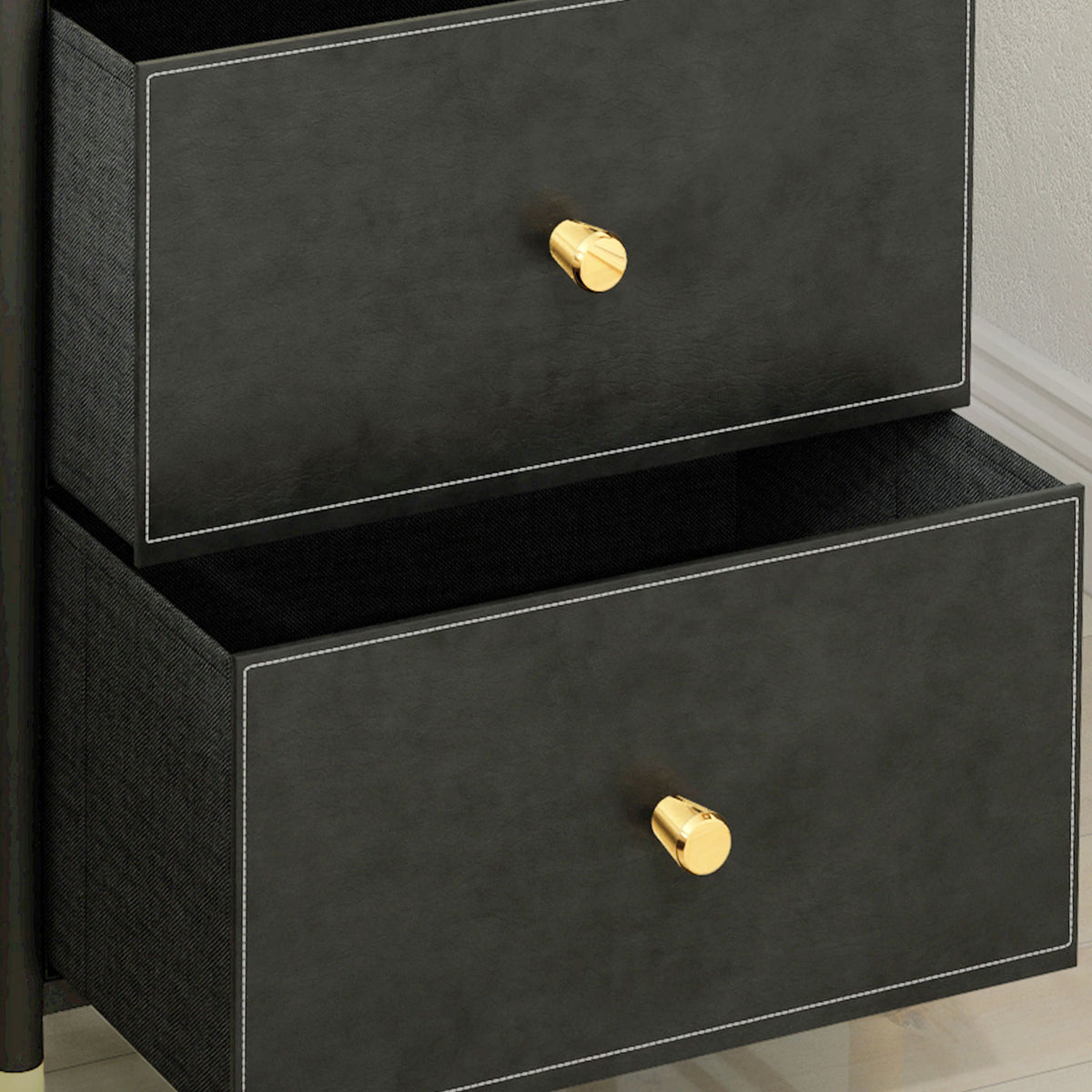 Close-up of two open drawers with black faux leather fronts and gold-tone knobs