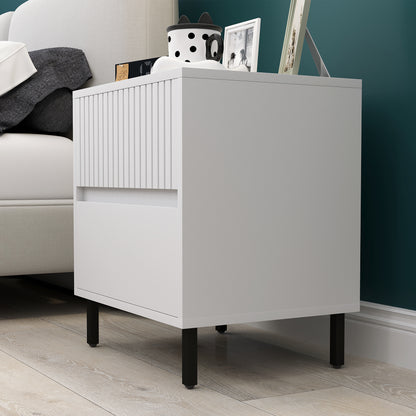White bedside table shown from the side, with grooved drawer fronts and black legs