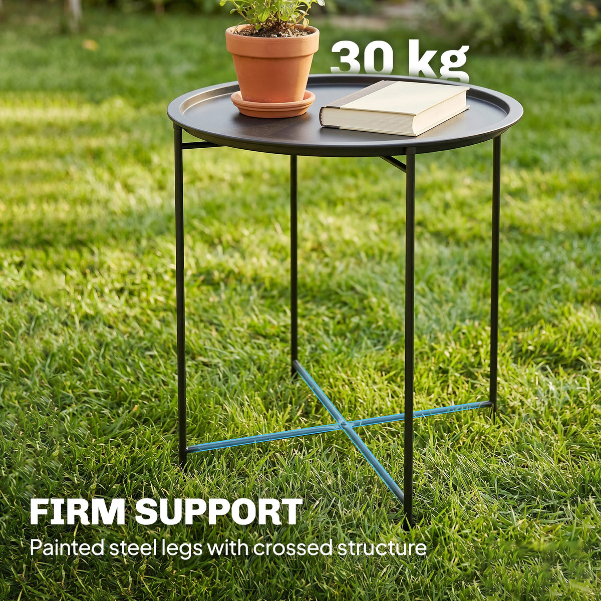 Outsunny black steel tray table with crossed leg supports, holding a plant and book