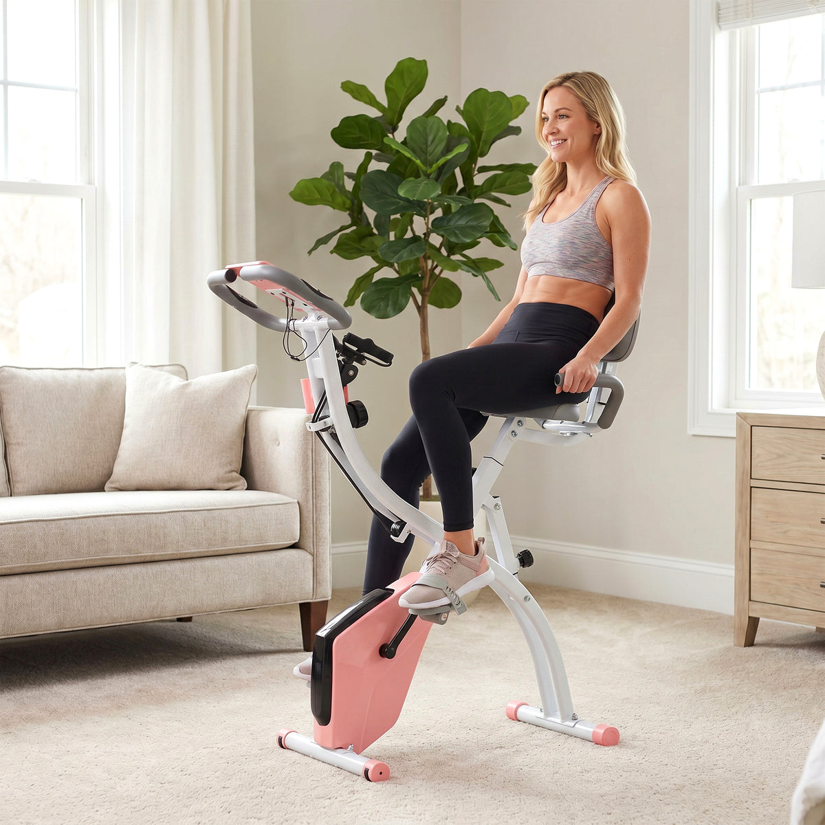 Pink and white folding exercise bike with padded seat and backrest, shown in use.