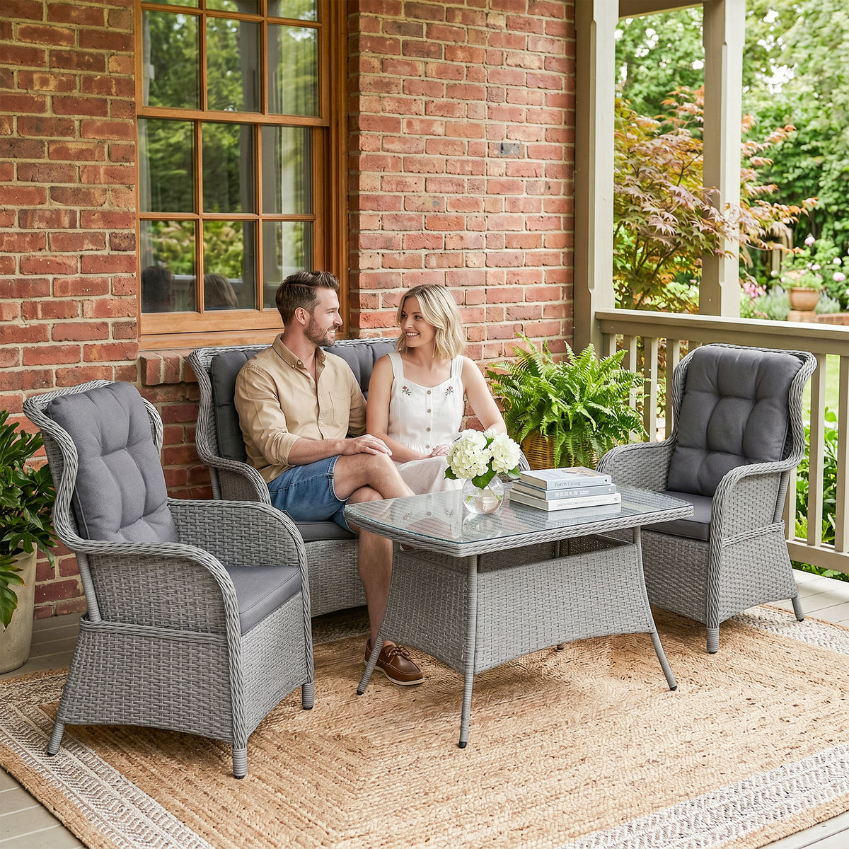 Gray wicker patio set with two cushioned armchairs, loveseat, and rectangular glass-top table